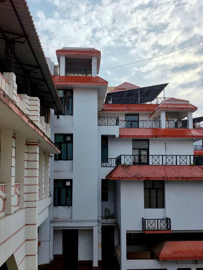 Contemporary white buildings with red roofs under a cloudy sky, showcasing modern architectural design.